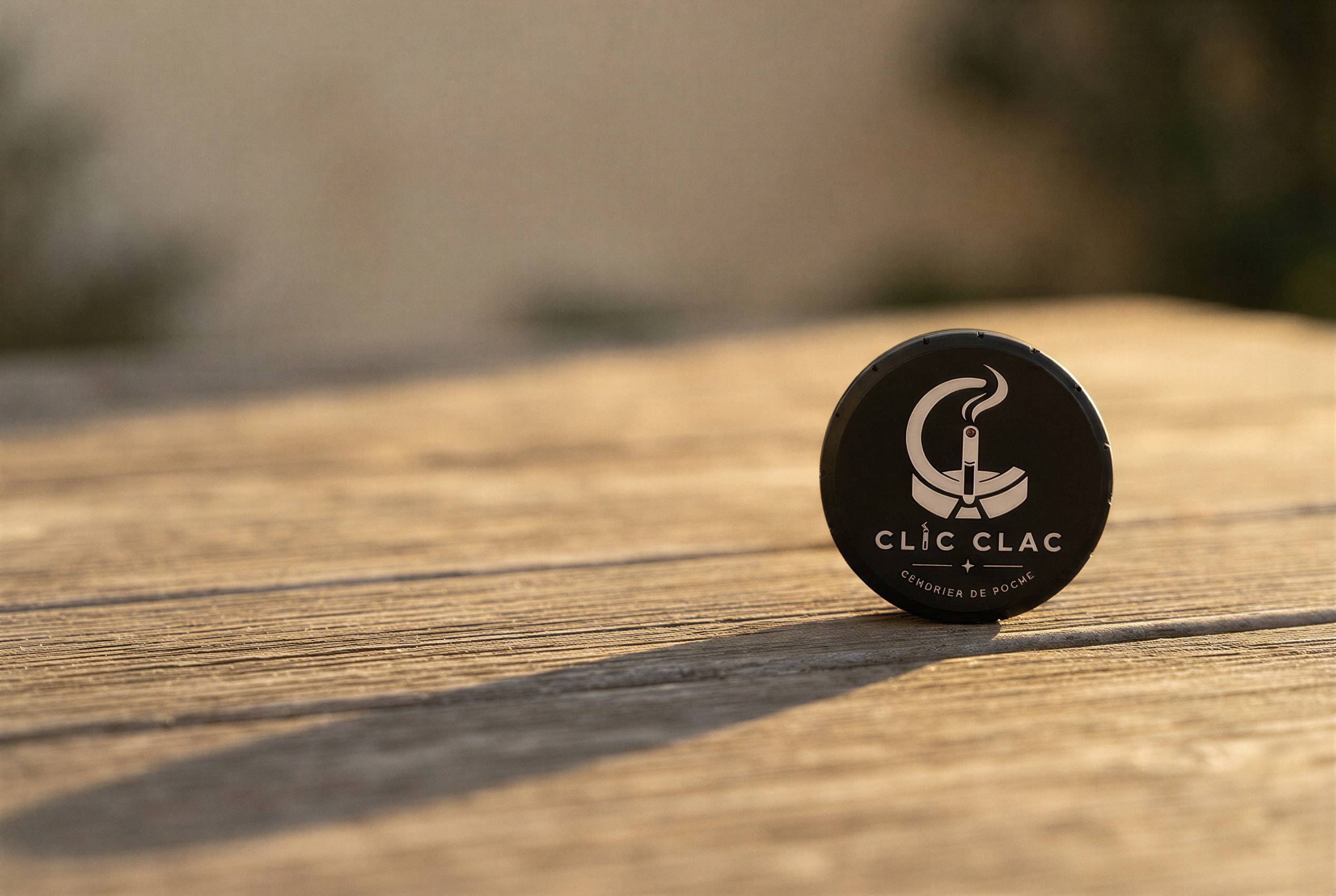 Un CLIC CLAC noir debout sur une table en bois, au soleil du soir.
